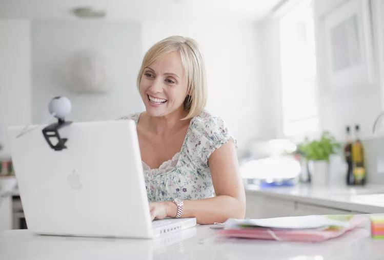 Женщина с помощью веб-камеры на портативном компьютере
